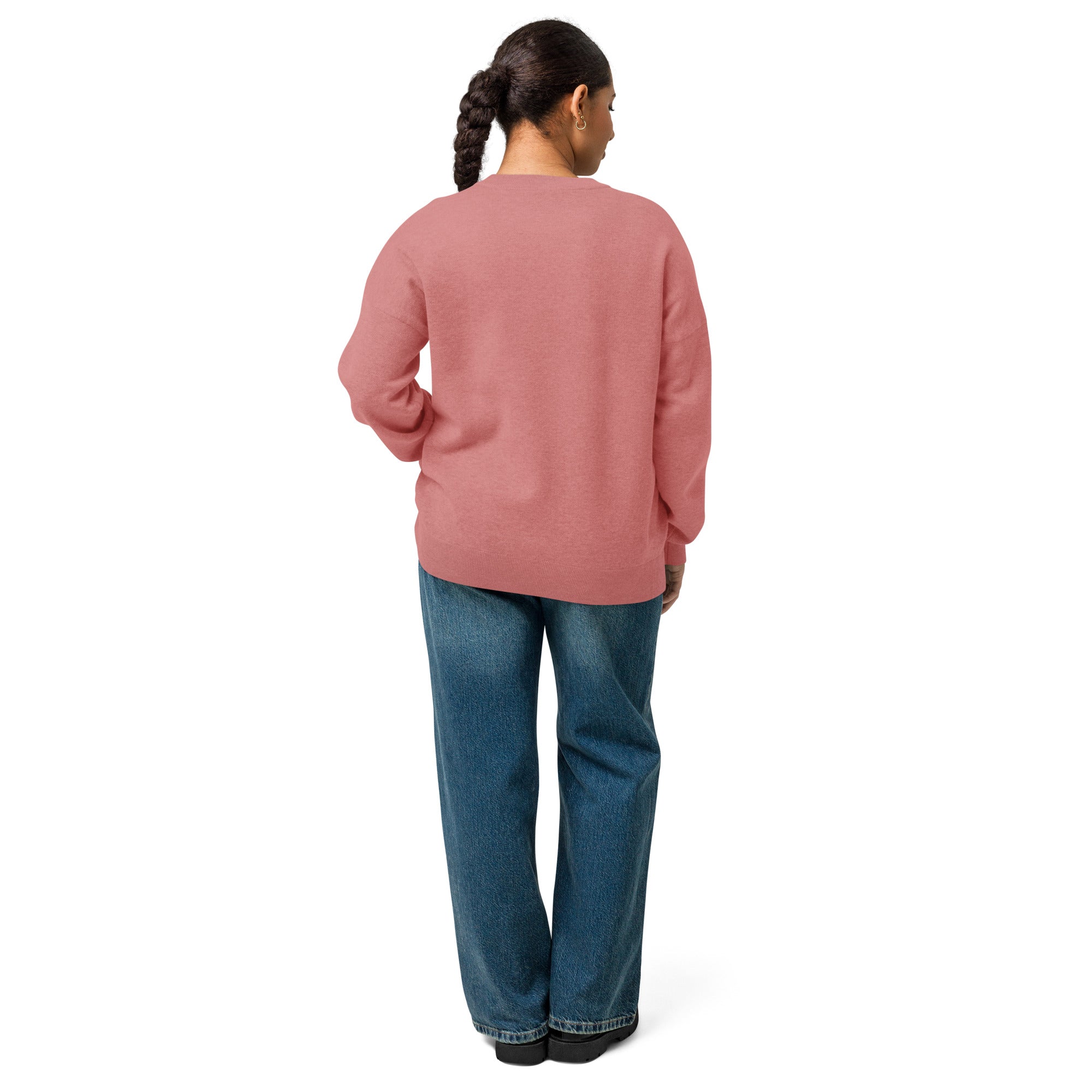Back of woman wearing pink knitted sweater standing looking to right shoulder with left arm bent