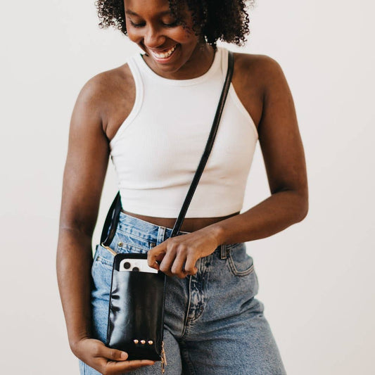 Double Duty Phone Crossbody Wallet Wallet by Pretty Simple black front worn on model crossbody style with model looking down at bag smiling and hands holding bag