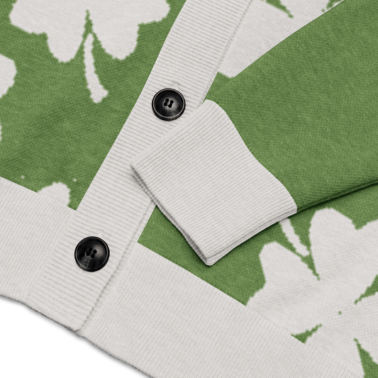 Close-up of a green cardigan with four-leaf clover patterned fabric with white trim, and button closure