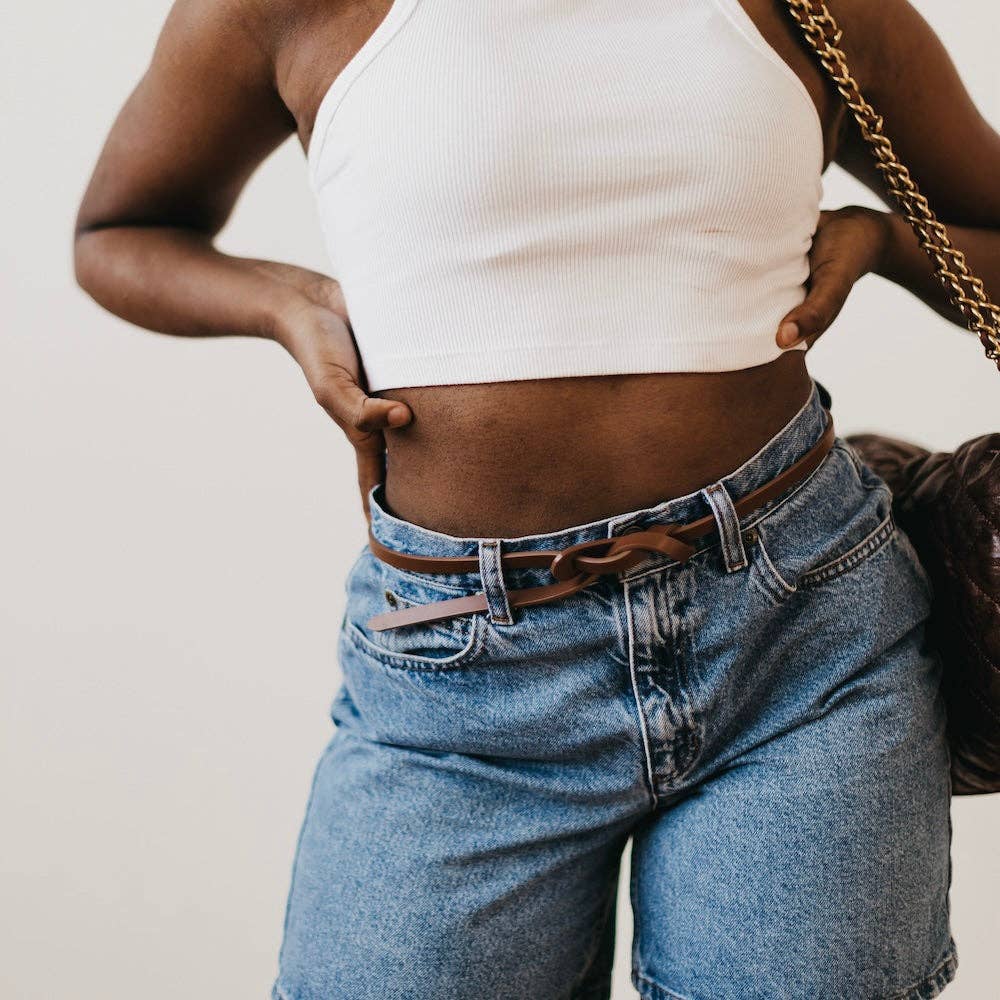 Lydia Vegan Leather Belt Belt by Pretty Simple brown on model holding waist tied into intricate knot on jeans