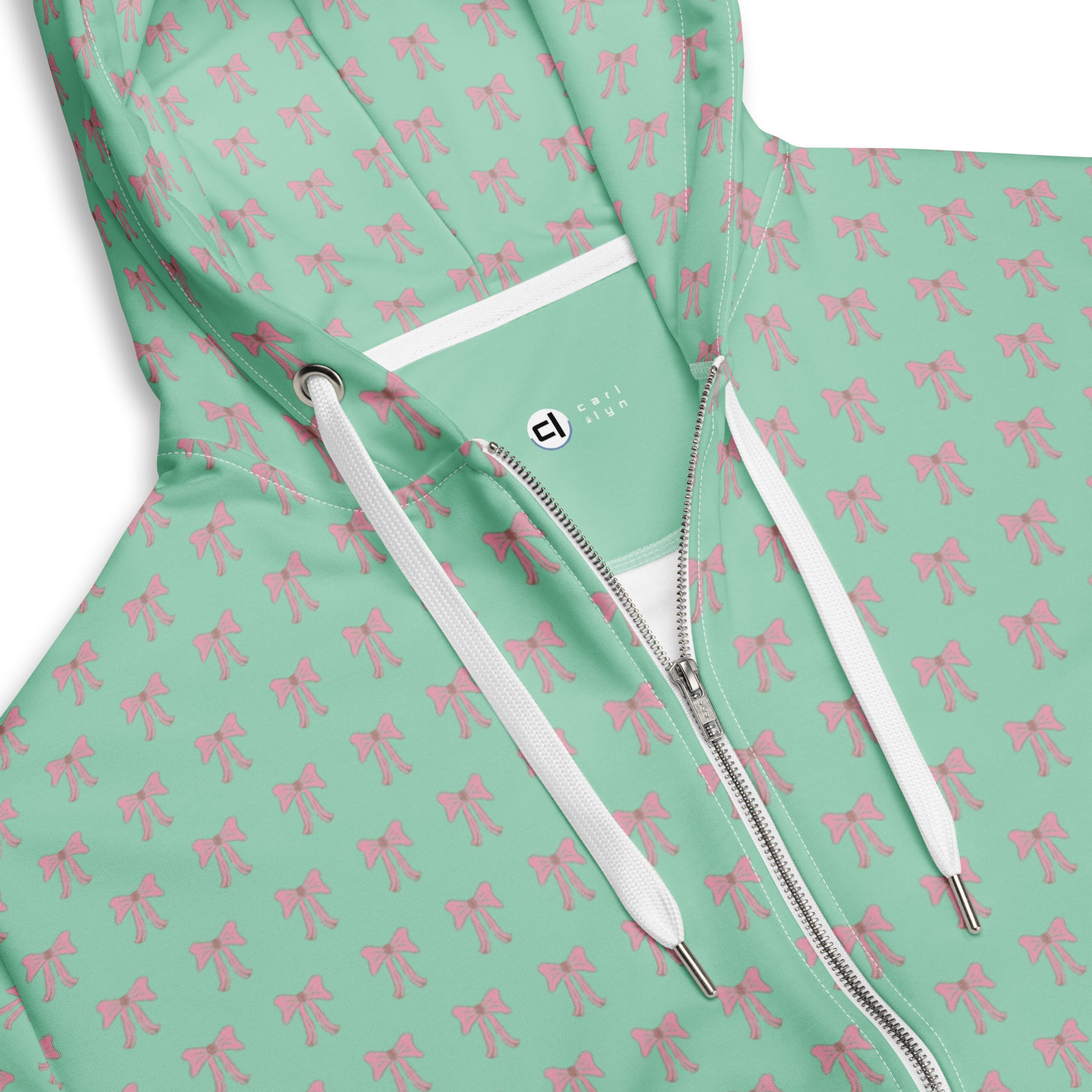 Zoomed in view of front collar, zipper, and drawstrings on Green hoodie with pink bow pattern and white zipper partially zipped