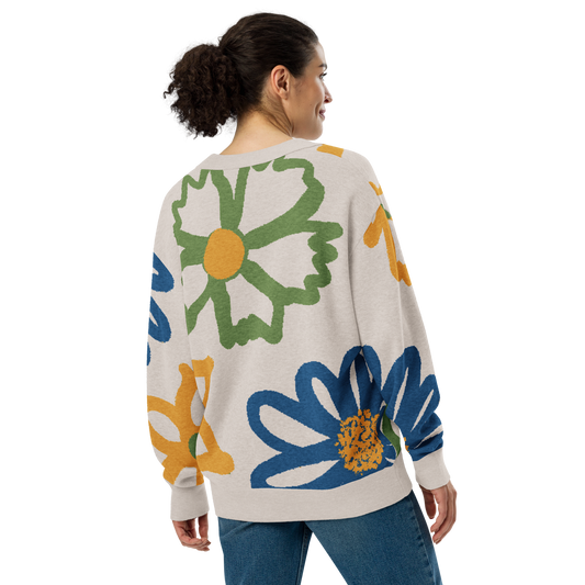 Back of Woman wearing a off-white cardigan with colorful floral designs, wearing blue jeans