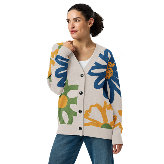 Front of Woman wearing a colorful floral cardigan that is buttoned up, wearing blue jeans with right arm bent toward face