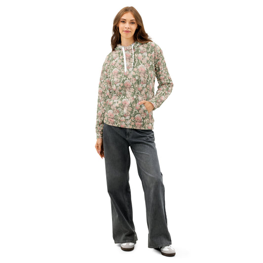 Front of Woman wearing a olive green base with pink and white floral patterned hoodie and gray pants, left hand is in hoodie pocket