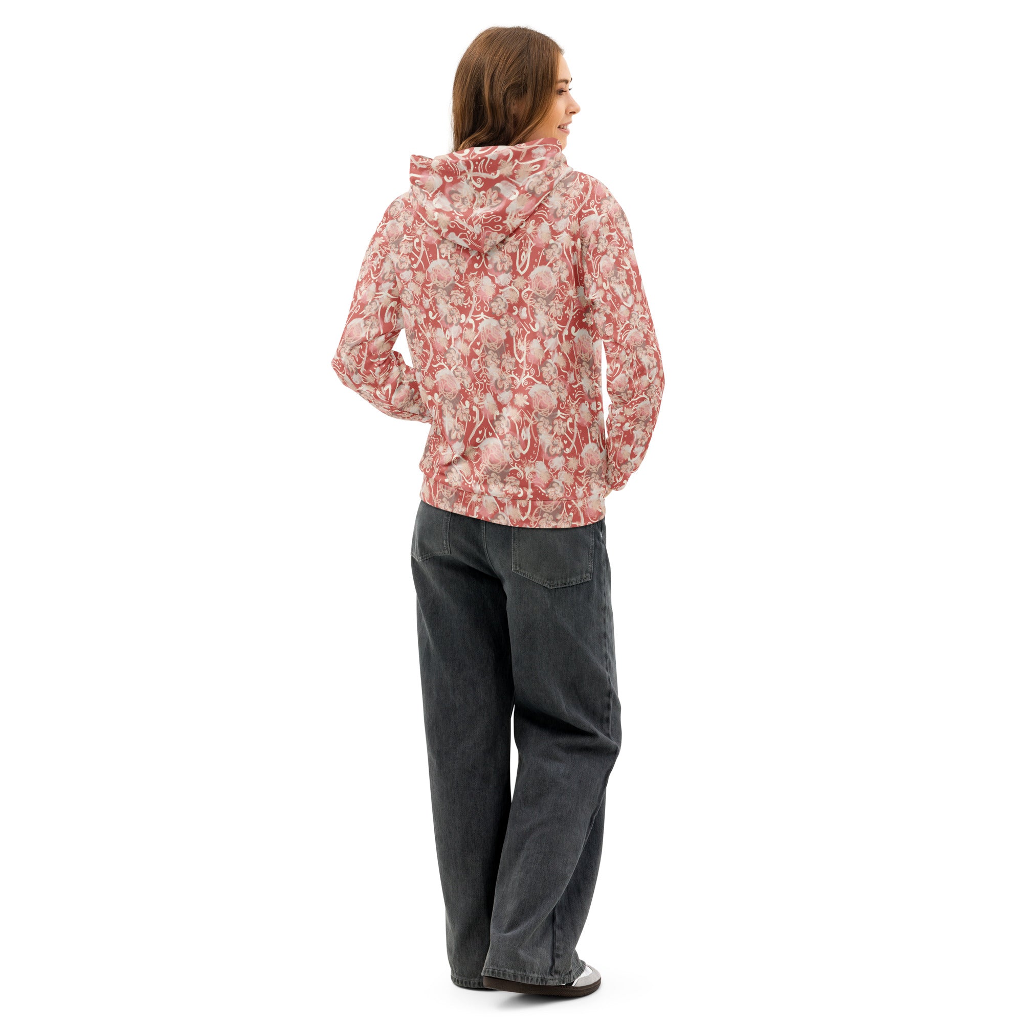 Back left of woman wearing a watermelon pink-colored, floral hoodie and gray pants , looking over left shoulder smiling