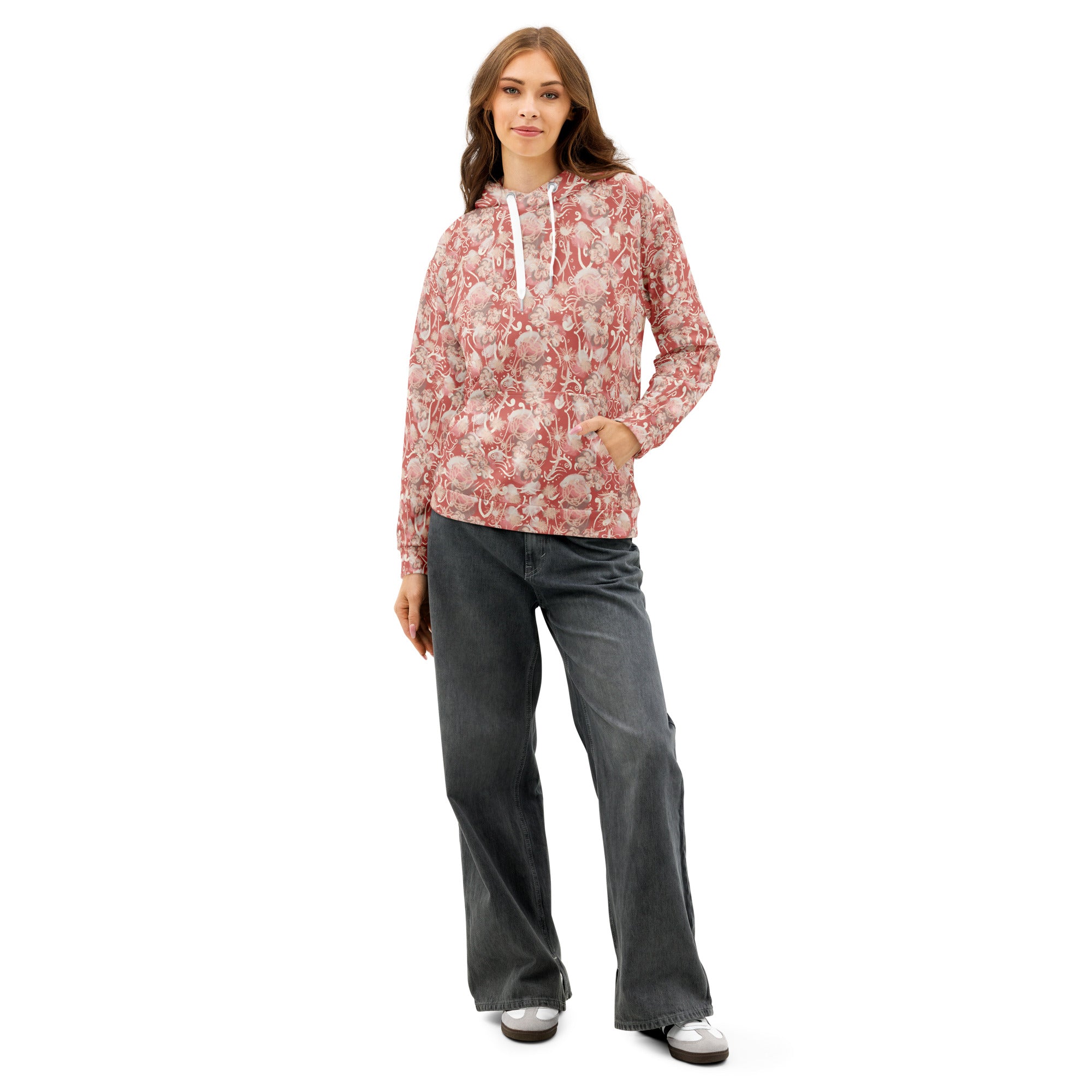 Front of Woman wearing a watermelon pink-colored, floral patterned hoodie with pocket and gray pants 