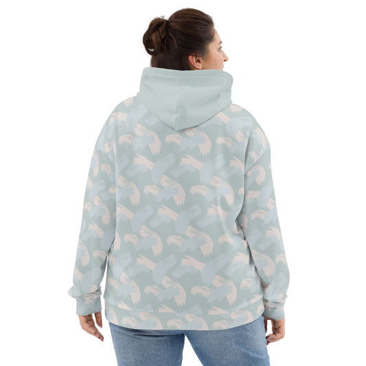 Back of Woman wearing a light blue hoodie with abstract pattern of paint strokes in multiple colors and solid hood looking right smiling
