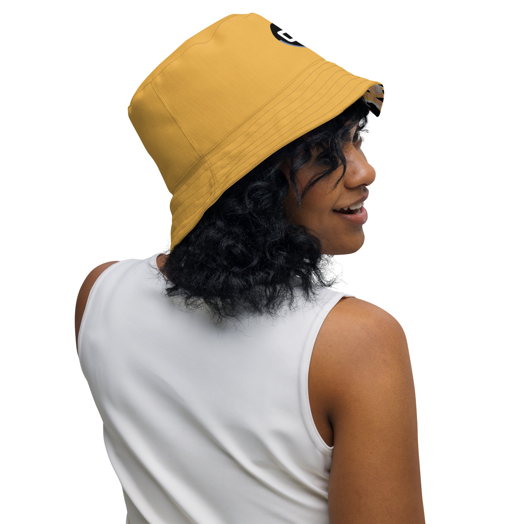 Person wearing a yellow mustard reversible interior of bucket hat looking over right shoulder and smiling
