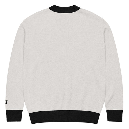 Back of Cream cardigan with black trim with branded logo "CL" near left wrist in black