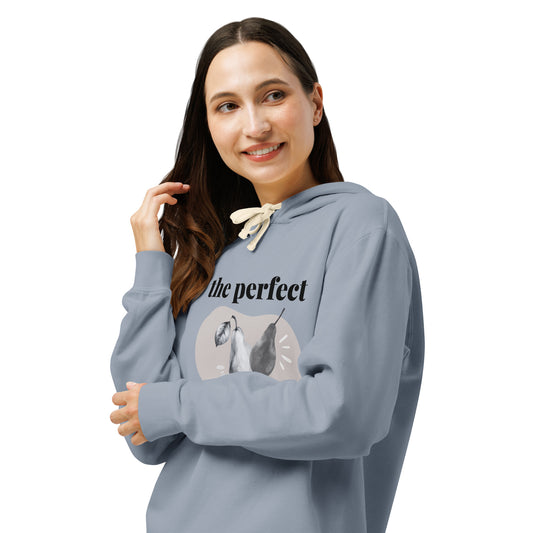 Front left of Woman wearing a denim blue hoodie with a graphic design, arms folded and looking left smiling